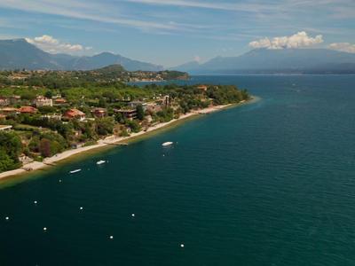Küstenlinie mit Dorf und Bergen im Hintergrund unter blauem Himmel neben ruhigem Meer