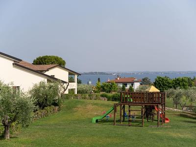 Garten mit Spielplatz und mehreren Häusern bei klarem Himmel