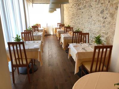 Restaurante elegante con suelos de madera, manteles blancos y pared de piedra.