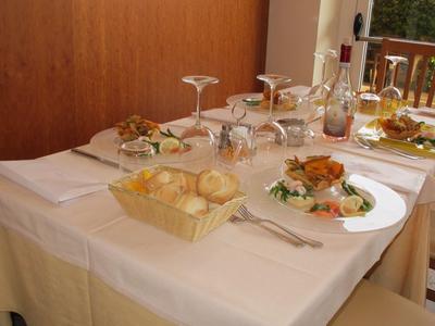 Mesa de restaurante con mantel blanco, pan, bebidas y platos servidos.