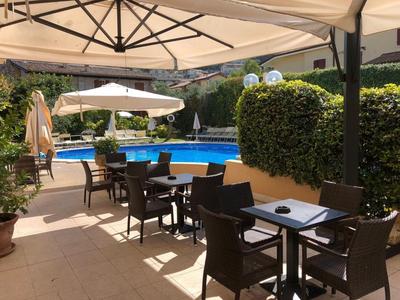 Zona exterior con mesas, sillas y sombrillas junto a una piscina de hotel.