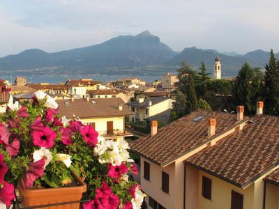 Blick auf ein Dorf mit roten Dachziegeln und Bergen im Hintergrund bei klarem Himmel.