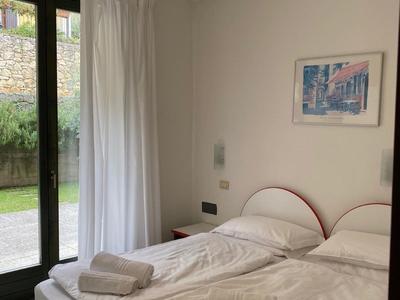 Habitación de hotel luminosa con dos camas individuales, cortinas blancas y un cuadro en la pared.