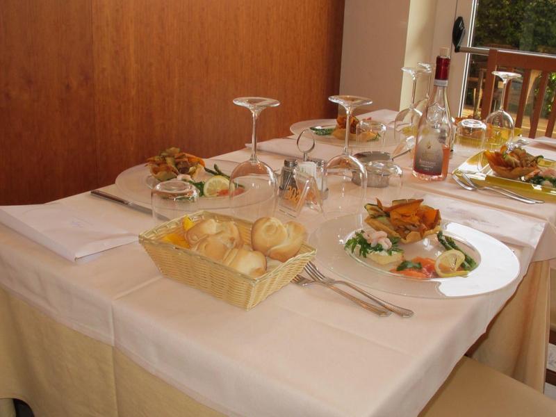 Mesa de restaurante con mantel blanco, pan, bebidas y platos servidos.