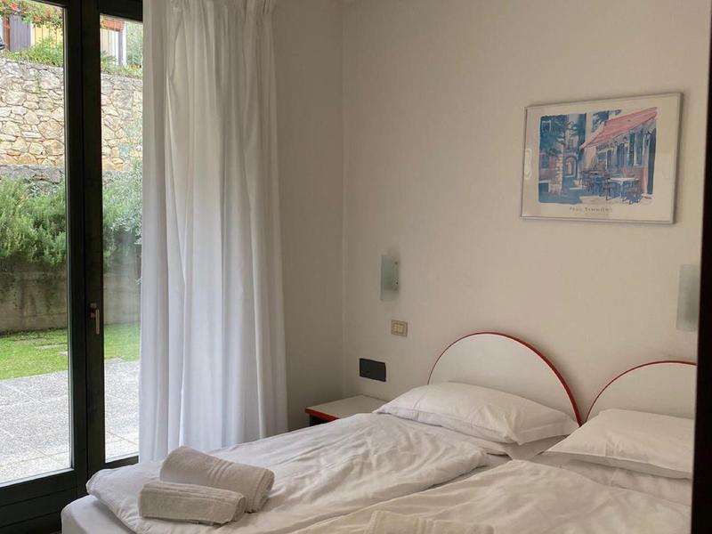 Habitación de hotel luminosa con dos camas individuales, cortinas blancas y un cuadro en la pared.