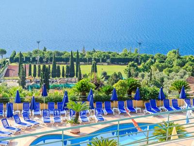 Widok na basen z niebieskimi leżakami i morzem w tle