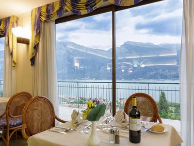 Tavolo da pranzo in un ristorante con vista sul lago e sulle montagne attraverso grandi finestre.