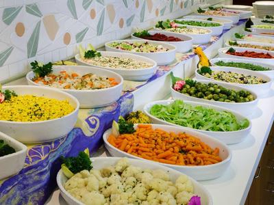 Różne miski z kolorowymi sałatkami warzywnymi i dodatkami na bufecie.