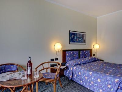 Pokój z podwójnym łóżkiem, stolikiem z butelką wina i dwoma krzesłami