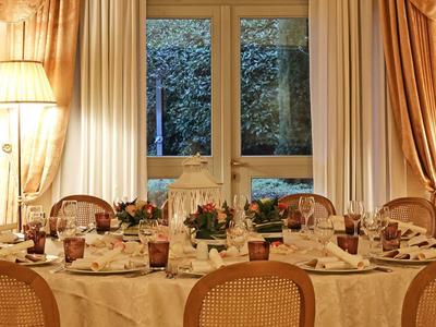 Table à manger élégante dressée avec vaisselle et chaises devant des fenêtres avec rideaux.