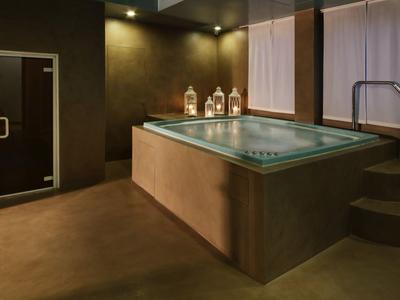 Espace bien-être moderne avec jacuzzi, éclairage tamisé et douche vapeur.