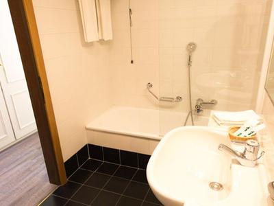 Kleines Hotelbadezimmer mit Waschbecken, Spiegel und Handtüchern neben weißer Tür.