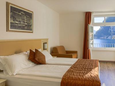Hell eingerichtetes Hotelzimmer mit Doppelbett, Stuhl, Schreibtisch und Fenster mit Bergblick.