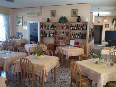 A cozy restaurant with multiple tables, yellow tablecloths, and a wall with wine racks.