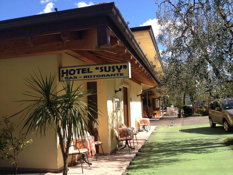 Hotel mit Terrasse, gelbe Fassade, grüner künstlicher Rasen und Autoschattierung im Freien.