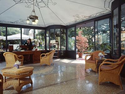Salon d'hôtel lumineux avec mobilier en osier, grandes fenêtres et lumière du jour.
