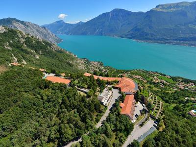 Vue d'un hôtel aux toits rouges à côté d'un grand lac turquoise entouré de montagnes.