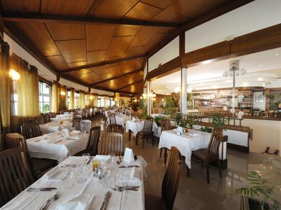 Restaurante elegante con manteles blancos y techo de madera con iluminación cálida.