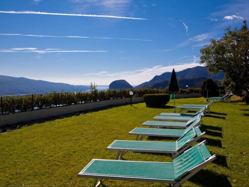Chaises longues vertes sur pelouse avec vue sur la montagne par temps ensoleillé.
