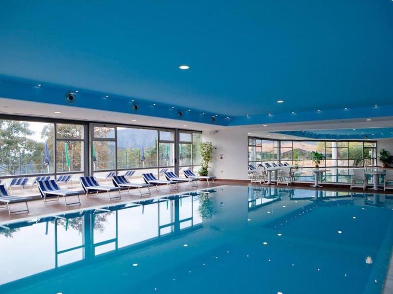 Piscine intérieure chauffée avec murs bleus et chaises longues près de grandes fenêtres