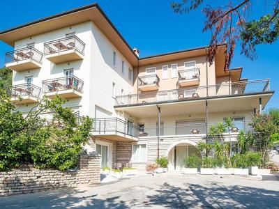 Edificio di hotel moderno con più balconi e verde sotto un cielo sereno.