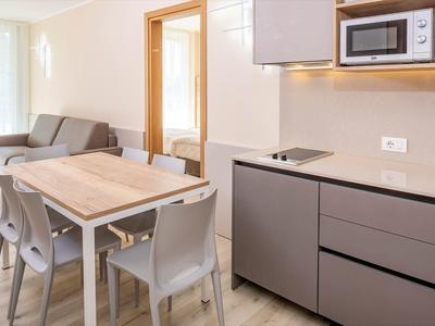 Cuisine et coin repas modernes avec mobilier gris et table en bois dans un appartement de vacances.