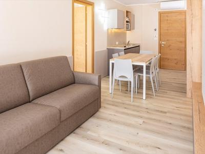 Salon moderne avec canapé gris, table à manger et cuisine ouverte.