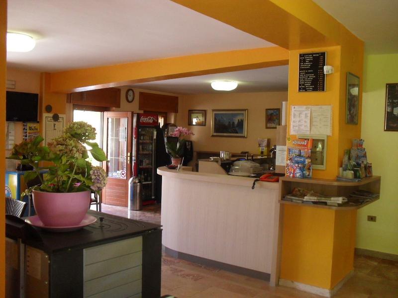 Accogliente banco ricevimento hotel con piante e pareti gialle in un interno invitante.