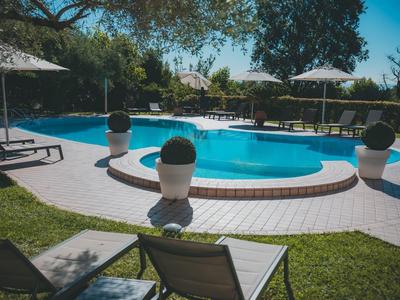 Kruhový bazén na zahradě s lehátky a slunečníky za slunečného počasí.