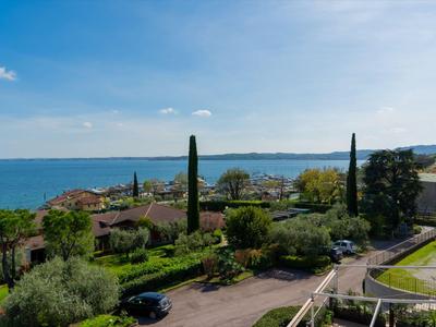 Blick auf eine Küstenlandschaft mit Meer, Bäumen und Häusern unter klarem Himmel.