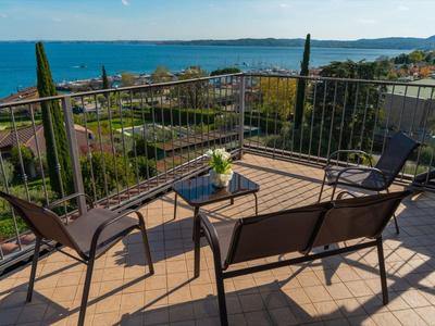 Terasa s židlemi a stolem, výhled na moře a pobřeží za slunečného počasí