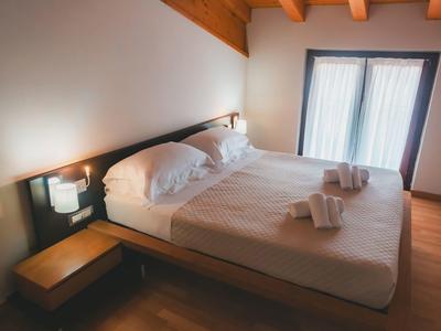 Przytulne łóżko podwójne w prosto urządzonym pokoju hotelowym z drewnianą podłogą i balkonem.