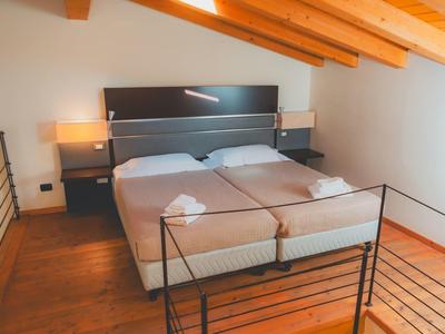 Dwa pojedyncze łóżka z szarą pościelą i drewnianym sufitem w prostym pokoju.