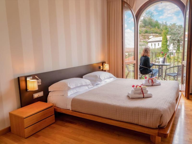 Jasny pokój z dużym łóżkiem i widokiem na balkon z naturalnym krajobrazem.