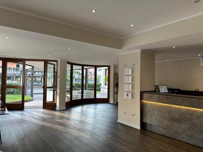 Moderner Empfangsbereich mit Glasfenstern, großzügigem Holzfußboden und beleuchtetem Tresen.