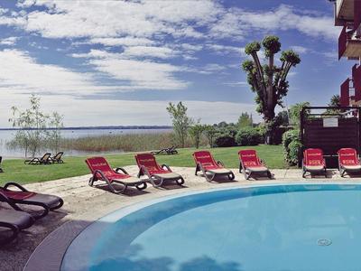 Piscina rotonda con sedie a sdraio rosse accanto a un hotel con vista su un paesaggio acquatico.
