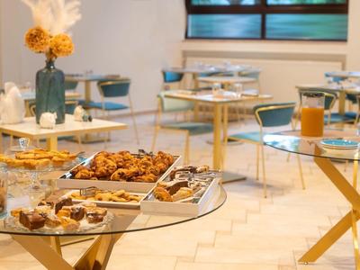 Allestimento buffet con pasticcini e prodotti da forno su tavoli di vetro in una sala da pranzo luminosa.