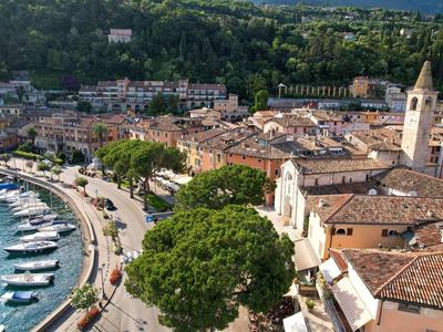 Vista di una città costiera con porto, barche e edifici storici sotto colline verdi.