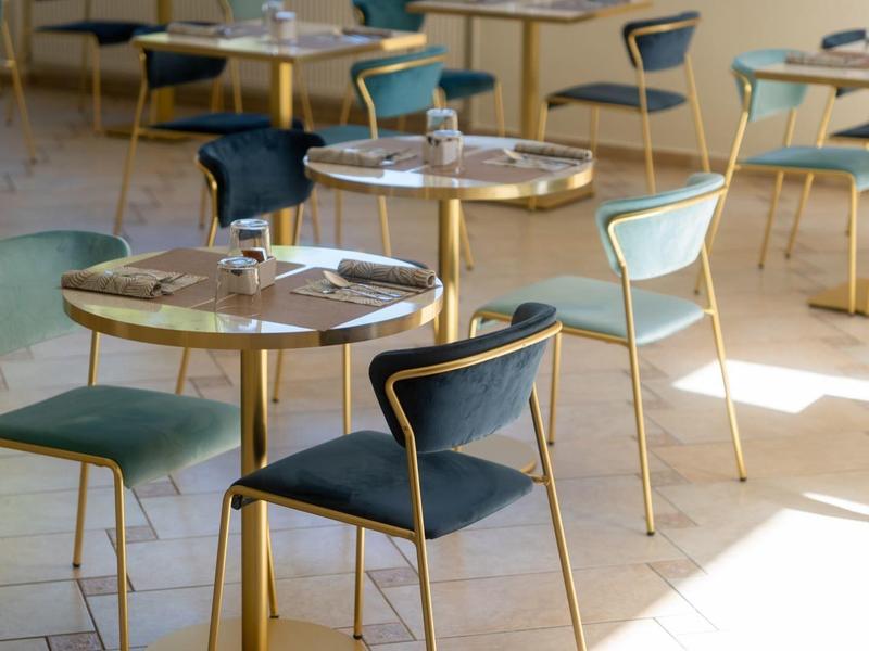 Sala colazione luminosa con tavoli e sedie in un hotel.