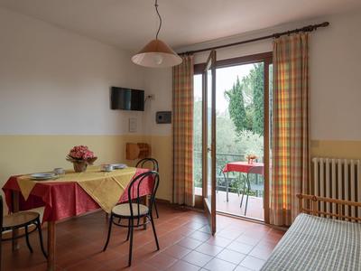 Camera d'hotel luminosa con tavolo, sedie e balcone con vista su alberi verdi.