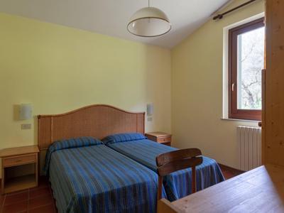 Camera d'albergo semplice con due letti singoli, biancheria a righe blu e una finestra grande.