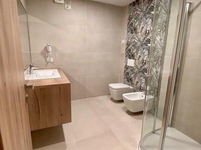 Bagno moderno con cabina doccia e piastrella decorativa in una struttura alberghiera.