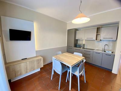 Piccola cucina moderna con tavolo da pranzo e sedie in una camera d'hotel.