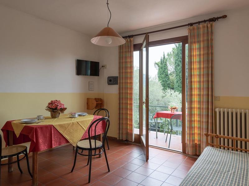 Camera d'hotel luminosa con tavolo, sedie e balcone con vista su alberi verdi.