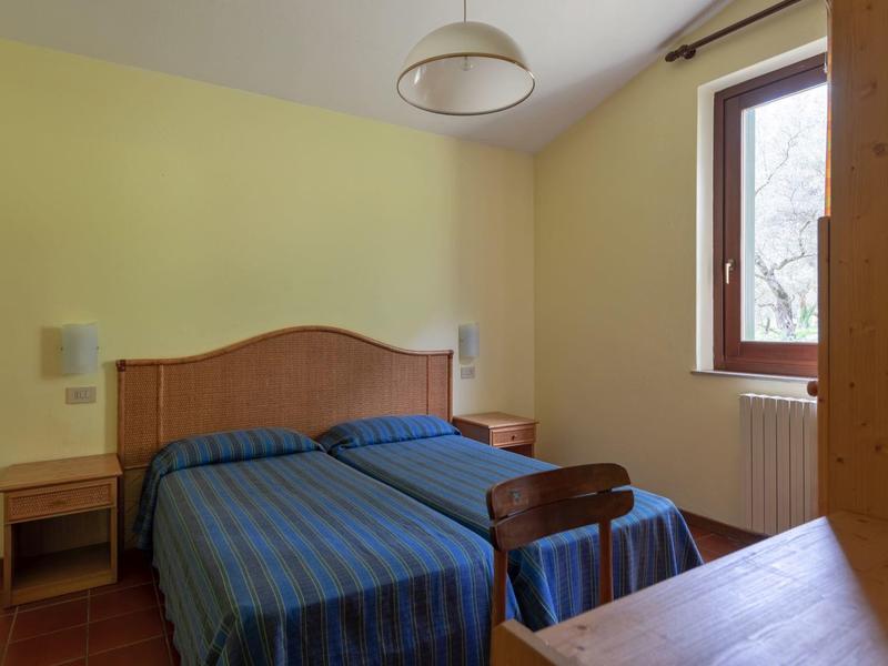 Camera d'albergo semplice con due letti singoli, biancheria a righe blu e una finestra grande.