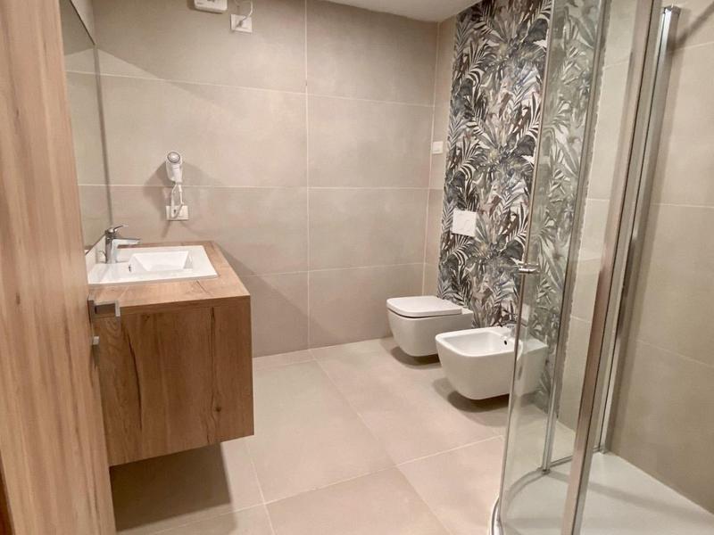 Bagno moderno con cabina doccia e piastrella decorativa in una struttura alberghiera.