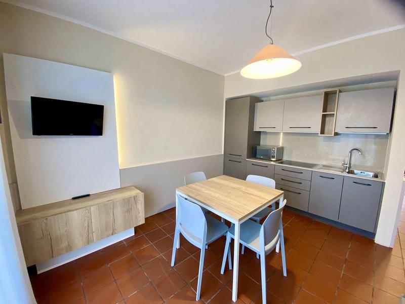 Piccola cucina moderna con tavolo da pranzo e sedie in una camera d'hotel.