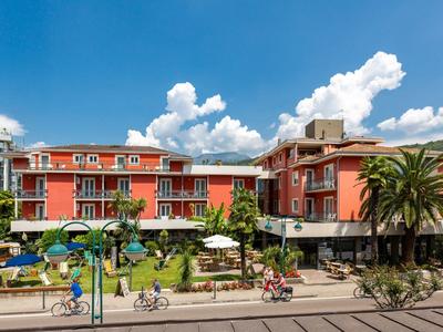 Hotel s bazénem a zahradou pod modrou oblohou s mraky