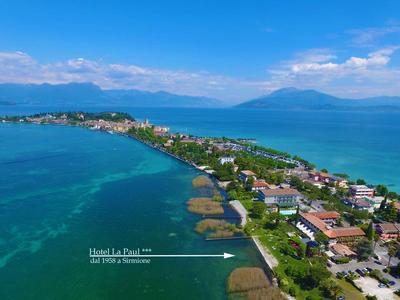 Langer schmaler Landstreifen mit Häusern, blauem Meer links und rechts, Bergen im Hintergrund.