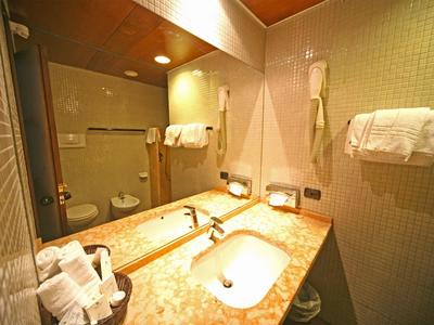 Helles Badezimmer mit Marmorwaschbecken, großen Spiegeln und Handtüchern an der Wand.